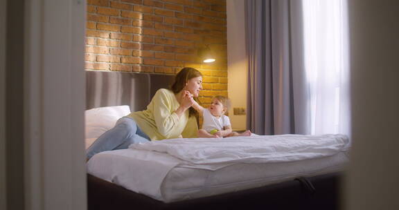 女人和她的孩子坐在家里床上的远景