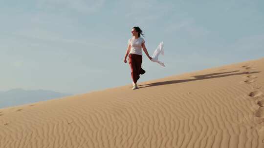 年轻美丽的欧洲女人在沙漠景观中行走