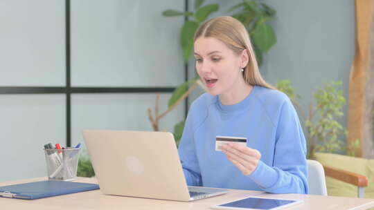 兴奋的女人用借记卡在线购物