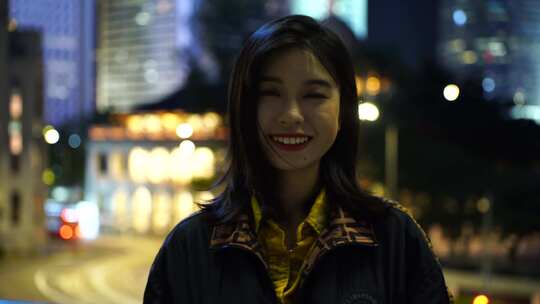 香港街头夜晚面对镜头微笑的女性青年开心笑视频素材模板下载