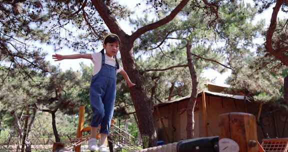 小女孩开心专注玩攀爬架独木桥