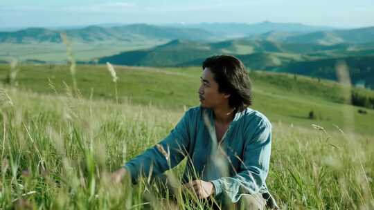 男子坐于草原草地眺望远方