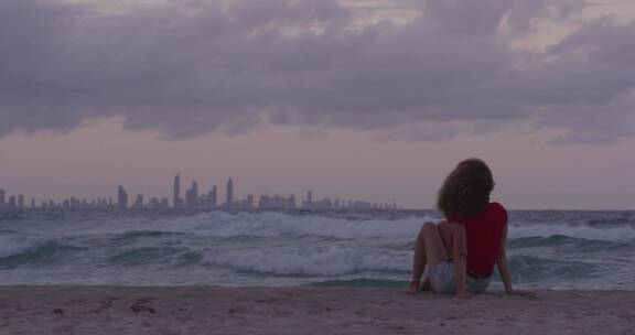 女子坐在海边观赏日落