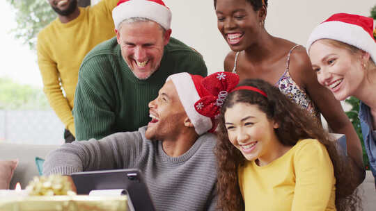 快乐的一群不同的朋友在圣诞派对上使用平板电脑进行视频通话