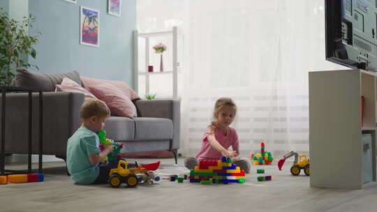 男孩玩玩具时，女孩用积木建造房子