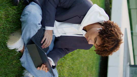 严肃的学生型笔记本电脑在城市公园垂直放松