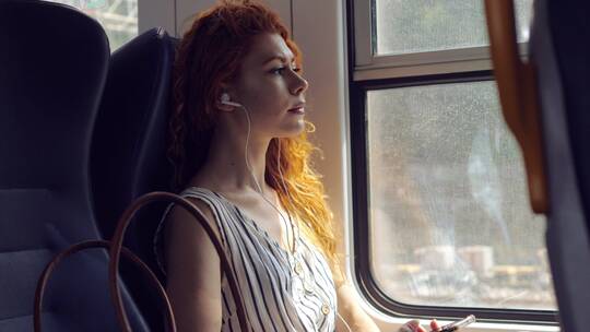 坐火车的女人戴着耳机听音乐