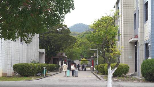 学生开学推着行李去宿舍楼工厂打工拖行李箱