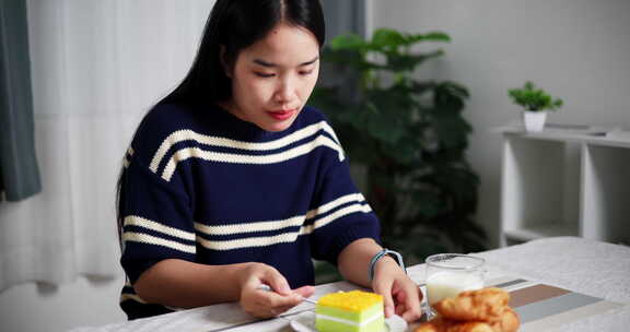 年轻的亚洲女人喜欢在家里的餐桌上吃早餐。