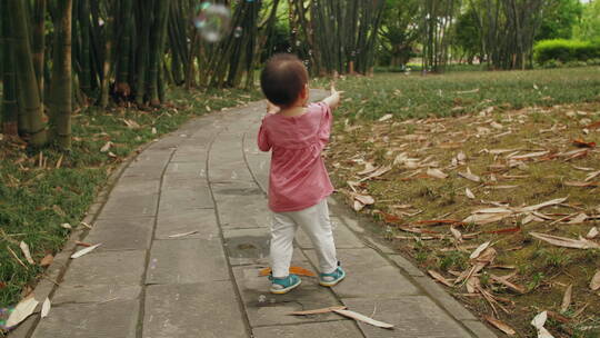 蹒跚学步的可爱小婴儿在公园里玩耍追逐泡泡