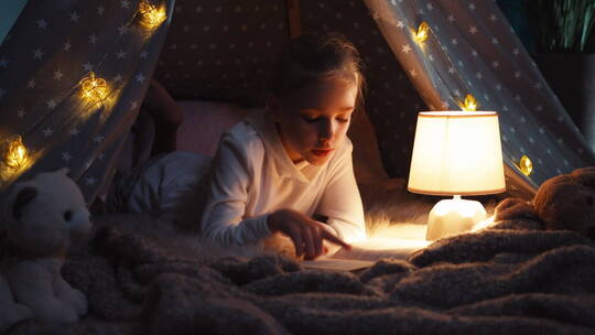 趴在床上台灯下看书的女孩
