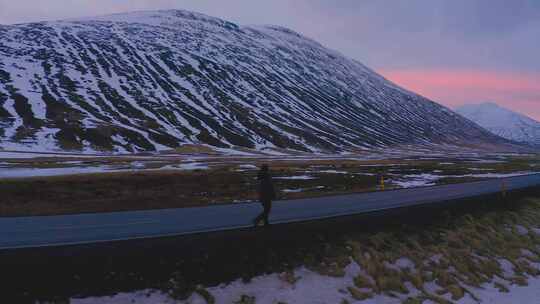 日落时分，一个人走在雪山边的路上