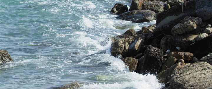 蓝水在白天以慢动作流到岸边的岩石上