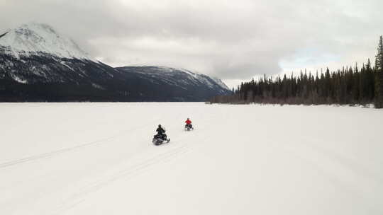 无人机拍摄了两个人在结冰的湖上骑雪地摩托。