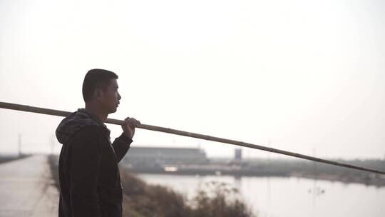 肩扛竹竿的渔民堤坝上行走视频素材模板下载