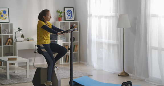 开朗的女士独自在家训练，白天在客厅健身和骑健身自行车