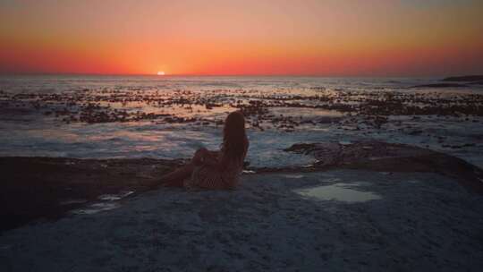 美女在海岸边坐着看夕阳