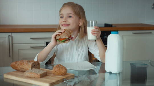 女孩坐在厨房桌子前吃面包喝牛奶视频素材模板下载