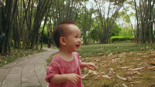 蹒跚学步的可爱小婴儿在公园里玩耍吹泡泡