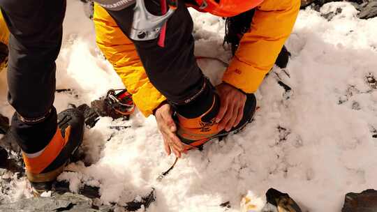 登山向导为攀登雪宝顶雪山的登山者穿戴冰爪