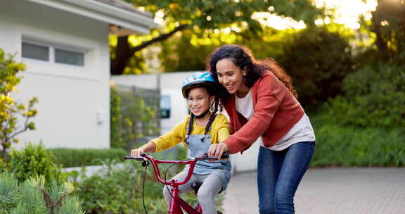 妈妈，孩子和教自行车户外在家里的车道上为