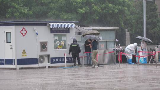 暴雨中维持核酸检测点秩序的医护们