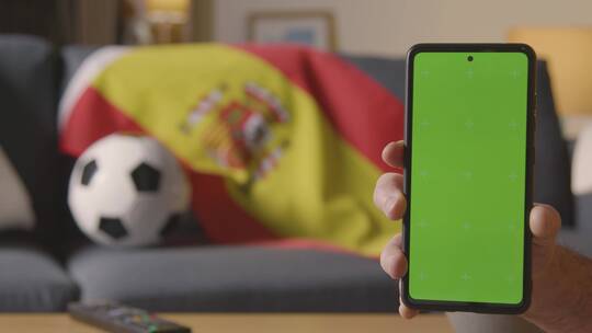 西班牙国旗和足球前的绿屏手机