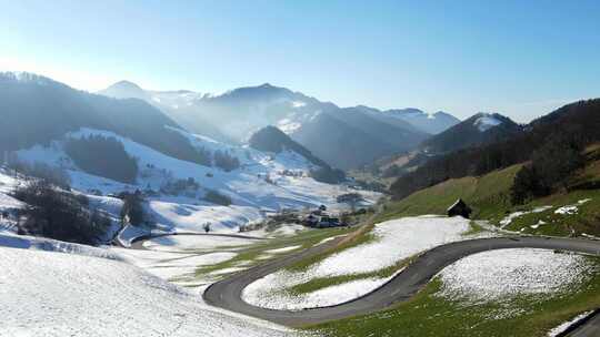 白雪覆盖的山谷中蜿蜒道路的无人机镜头