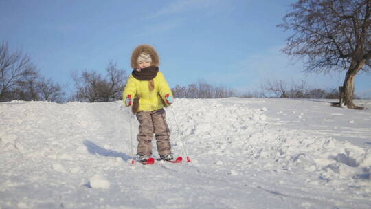 小女孩小心的在雪地玩滑板