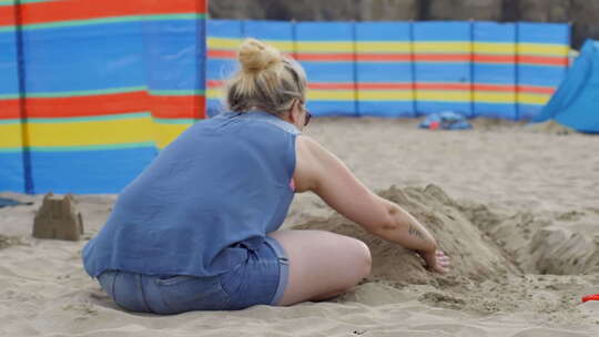 女人在海滩上建造沙堡视频素材模板下载