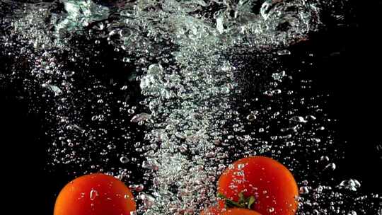 四个红色的番茄掉入水中慢镜头