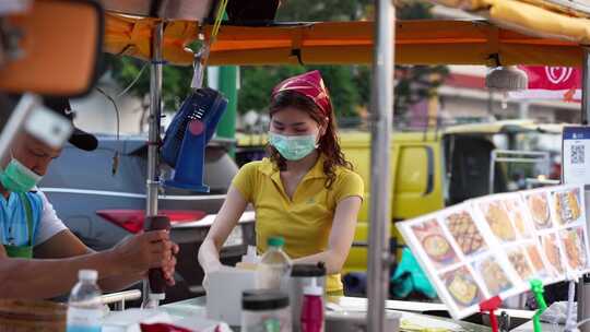 一个戴口罩的女人在卖食物