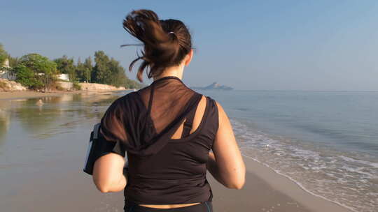 运动女人沿着海滩跑步的后视图