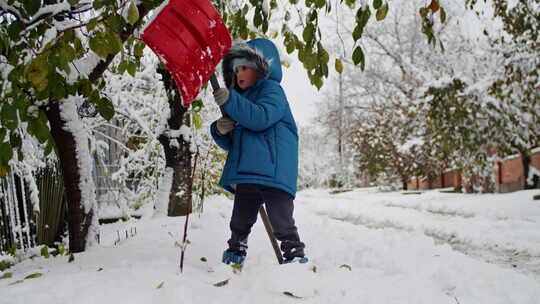 在寒冷的暴雪娱乐中，一个孩子铲雪的努力点视频素材模板下载
