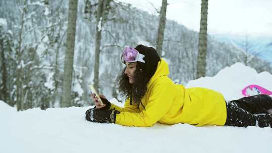 女人躺在雪地上用手机自拍