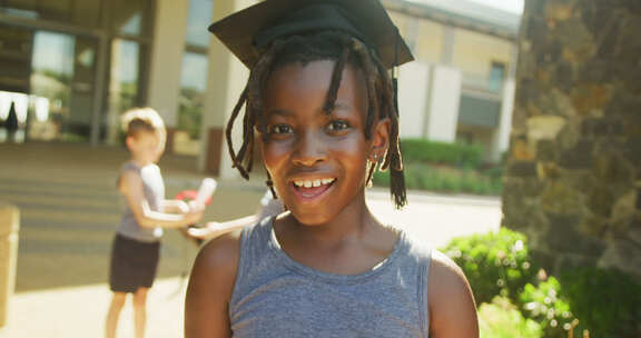 快乐的非裔美国男孩戴着毕业帽，拿着文凭在学校前的视频