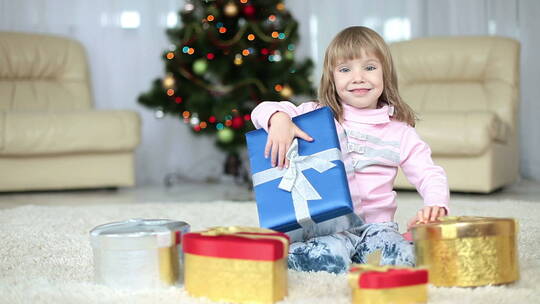 女孩抱着圣诞礼物坐在地毯上