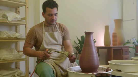 男性工匠在工匠车间使用喷灯加热粘土花瓶雕视频素材模板下载
