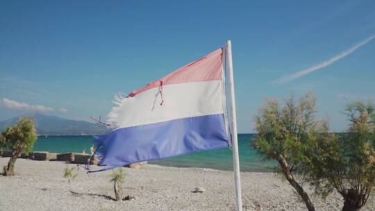 撕裂的红白蓝三色旗帜在海滩上飘扬