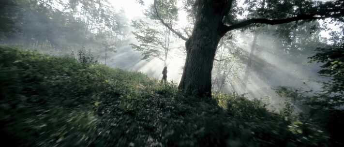 航拍清晨森林雾气下行走的美女丁达尔光
