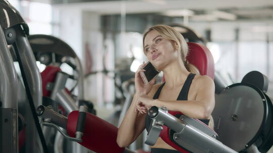 女人坐在健身器材上打电话视频素材模板下载