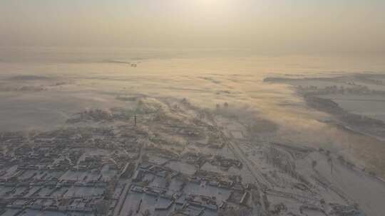 被浓雾笼罩的雪后村庄全貌