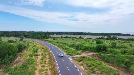 航拍一辆白车行驶在森林道路上