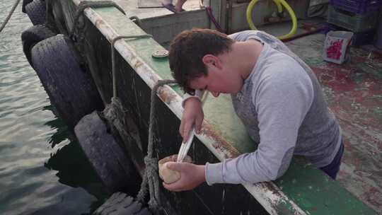一个小男孩在船上清理贝壳