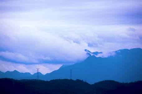 云雾缭绕下的山峦与输电塔风景