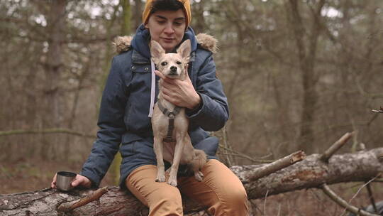 树林里女性抱一只小狗坐在树木上