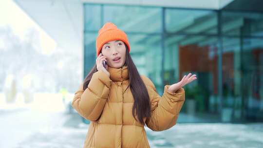 年轻的亚洲女人在手机上说话在一个下雪的冬