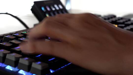 玩家打字和使用彩色键盘的手，一个无法辨认的人在玩的特写
