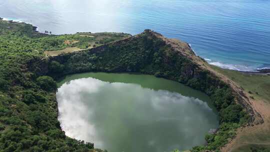 鸟瞰火山口湖，绿色的水被悬崖和绿色植物包