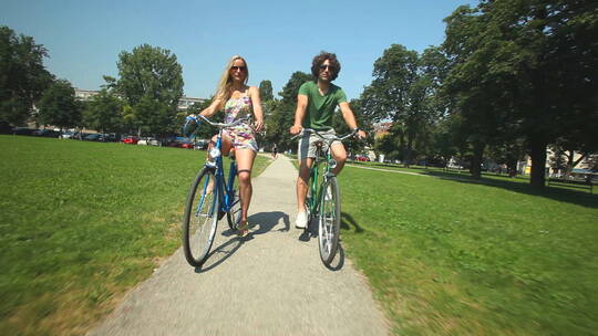 夫妇在夏天骑自行车穿过公园